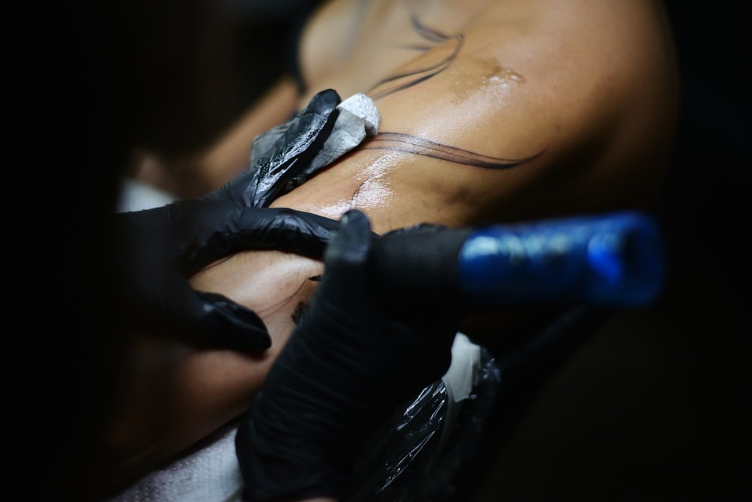 Close-up of tattoo artist applying ink to skin with professional equipment in modern studio